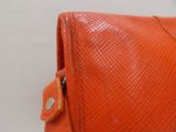an orange leather purse with a metal clasp on a white background