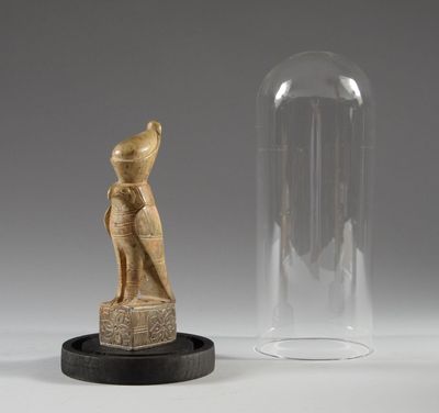 une figurine égyptienne et une cloche en verre posées sur une table