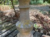 a stone vase sitting on a wooden bench in the woods