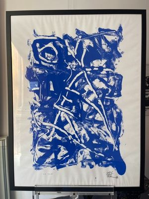 blue and white abstract painting in a black frame in a living room