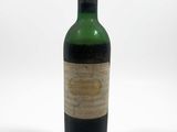 an old bottle of wine sitting on top of a white surface