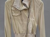 une photo d'une veste beige posée sur un portant en bois, sur fond gris
