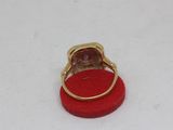 a gold ring with a pink stone in it on a red ring stand