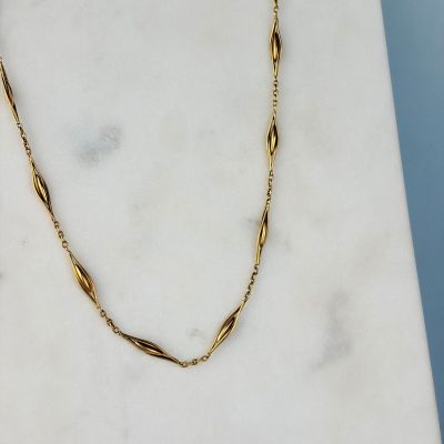 a picture of a gold necklace on a marble surface