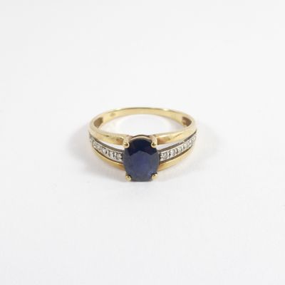 gros plan d'une bague en or avec une pierre bleue et des diamants