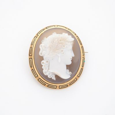 Une broche en or représente le profil d'une femme.