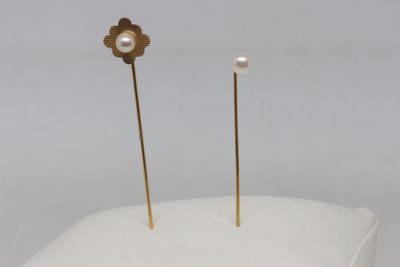 a pair of pearl and gold earrings on a white pillow