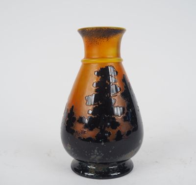 un vase noir et orange posé sur une surface blanche