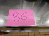 un autocollant rose sur une table en métal sur laquelle est posée une pancarte
