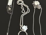a group of three silver necklaces with charms on them