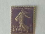 timbre violet et doré représentant une femme, sur un fond blanc