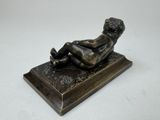 a bronze figurine of a woman laying on her stomach