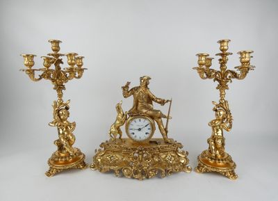 trois bougeoirs dorés et une horloge posés sur une table