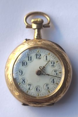gros plan d'une montre de poche en or sur une surface blanche
