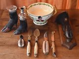 a table with a bowl, knife, spoon, and other items on it