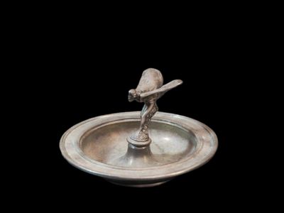 un oiseau argenté sur une assiette argentée, sur fond noir