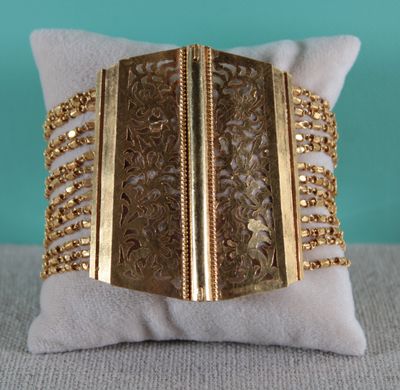 un gros plan sur un oreiller sur lequel repose un bracelet en or