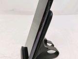 the back view of a cell phone on a stand on a white surface