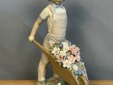 une figurine représentant un garçon avec une brouette et des fleurs