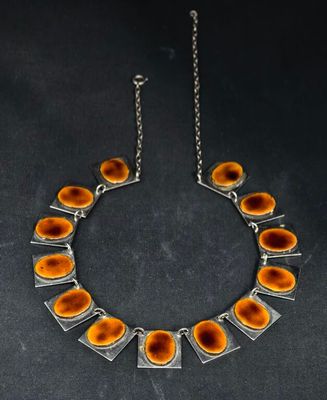 un collier composé de cercles orange et argentés sur fond noir
