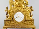 a gold clock with an angel sitting on top of it