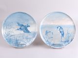 deux assiettes avec des oiseaux peints dessus, posées sur une table