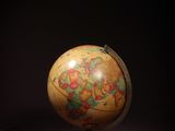 un vieux globe terrestre posé sur un socle dans l'obscurité, éclairé par une lumière