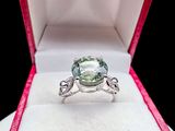 an image of a ring in a box with a green stone