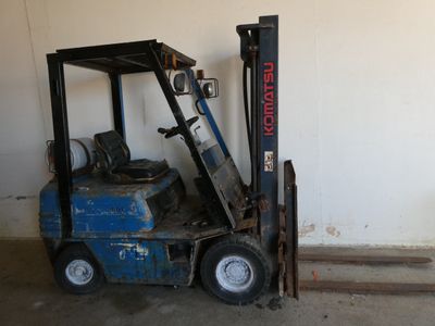 a forklift sitting in a garage next to a wall
