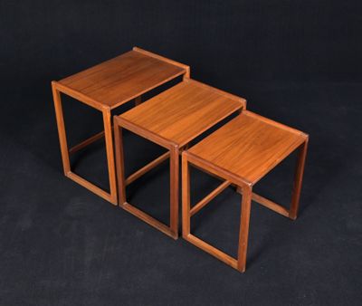 un ensemble de trois tables gigognes en bois sur fond noir