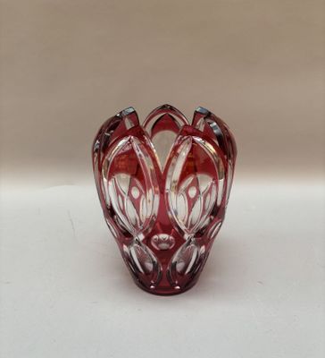 une image représentant un vase en verre rouge posé sur une surface blanche