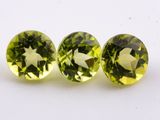 a pair of three green tourmaline gems sitting on top of a white surface