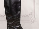 a pair of black leather boots sitting on top of a wooden table