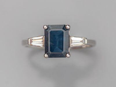un gros plan d'une bague sertie d'un saphir bleu et de deux pierres taillées en baguette