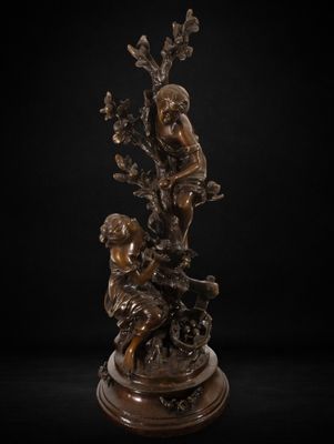 une statue en bronze représentant un garçon et une fille assis sur une branche d'arbre