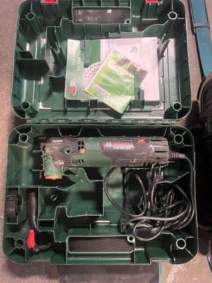 une boîte à outils verte posée par terre, contenant des outils