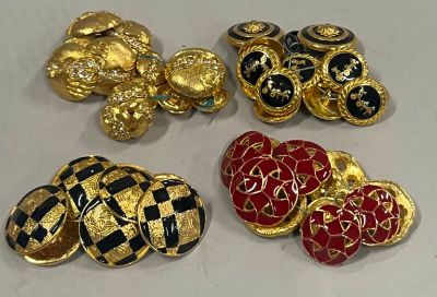 quatre broches dorées, noires et rouges sont posées sur une surface blanche