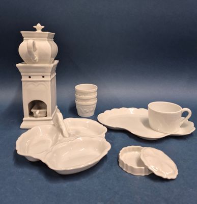 une photo d'un service en porcelaine comprenant une théière, une soucoupe, des tasses et des soucoupes