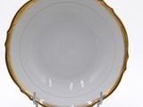 a white and gold plate with a gold rim on a stand