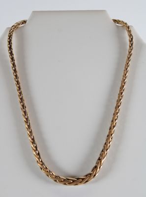 un collier à chaîne en or au motif torsadé sur un mannequin blanc