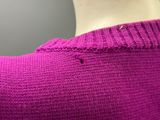 le dos d'un pull de femme qui porte un pull rose par-dessus