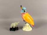 a figurine of a bird sitting on a rock next to a statue of a bird