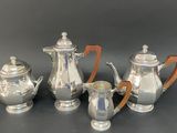 three pieces of silver tea and coffee set on a table