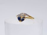 a close up of a gold ring with a blue sapphire and diamonds