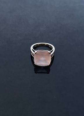 a pink stone ring sitting on top of a black surface