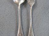 two silver spoons and a fork on a table