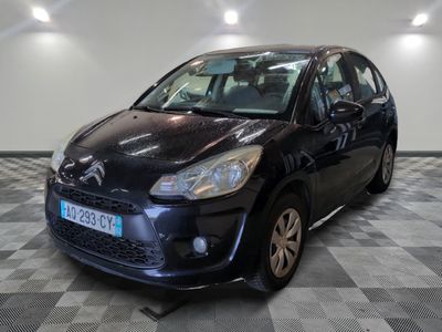 La petite voiture noire est garée dans le garage, sur le sol à damier.