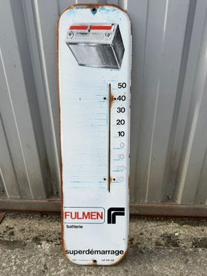 a white thermometer sitting on the side of a building