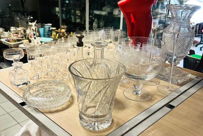 bottles and glasses on a table in a store with a red object in the background
