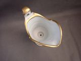 underside view of a white and gold urinal on a gray surface